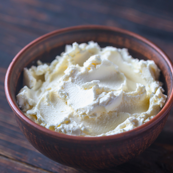 Pocillo con queso crema sobre mesa de madera