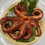 Pulpo cocido sobre una cama de hummus en un plato blanco