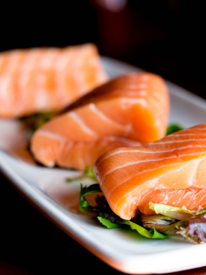 Salmón crudo con hojas verdes sobre plato blanco