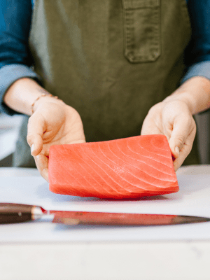 Cocinero tomando un trozo de salmón con sus manos