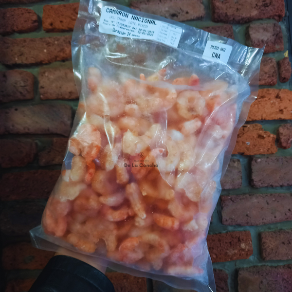 Bolsa de camarón nacional cocido congelado con el fondo de una pared de ladrillos