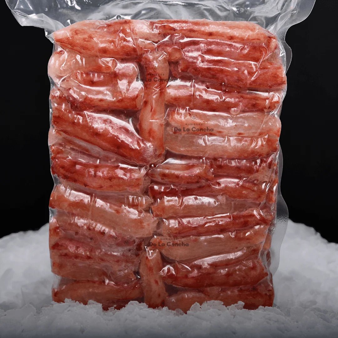 Carne de centolla congelada premium (Chilean King Crab) al vacío sobre una cama de hielo y fondo negro.