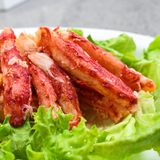 Plato de carne de patitas de centolla (Chilean King Crab) cocida sobre una cama de lechuga.