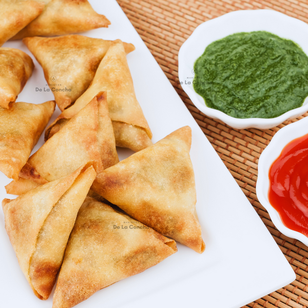 Empanadas triangulares de carne mechada con queso sobre plato blanco y salsas verde y roja