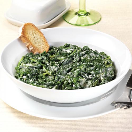Espinacas a la crema en plato blanco con pan