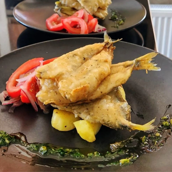 Pejerreyes fritos con tomate y limon sobre un plato negro