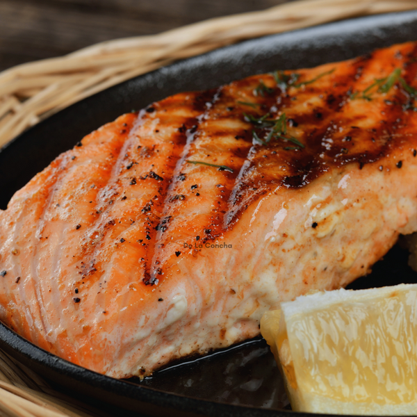 Porción de salmón grillada al limón en un plato negro