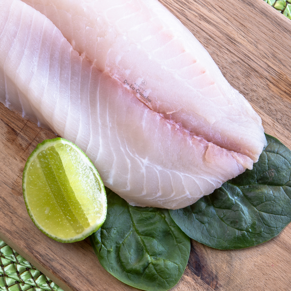 Filete de tilapia crudo sobre tabla de madera
