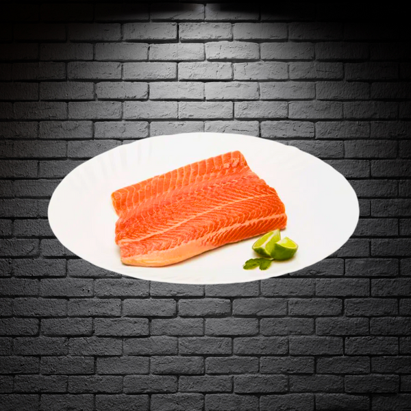 Trozo de trucha fileteada sin piel en un plato blanco sobre fondo de ladrillo negro 